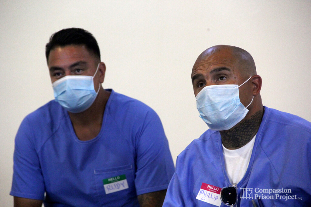 Two men sitting in masks