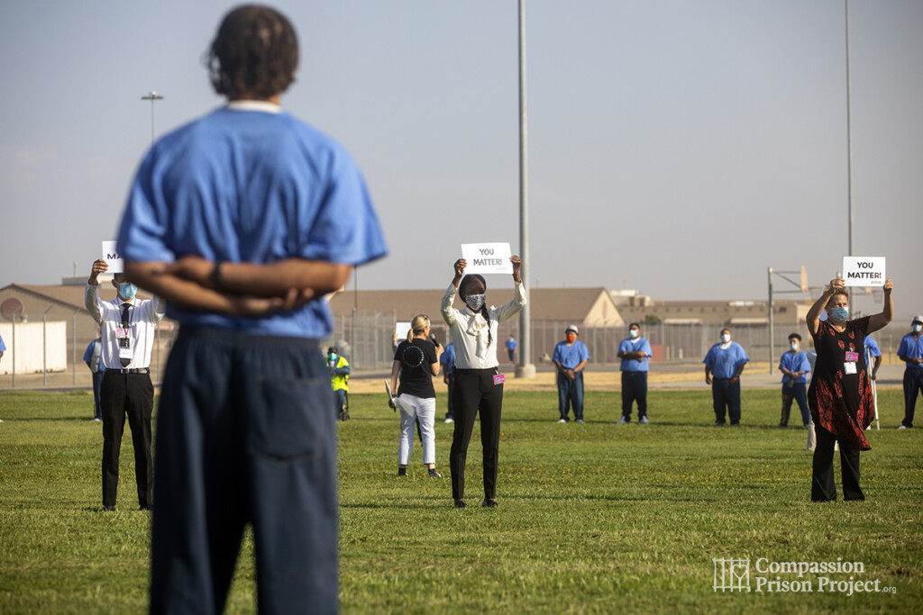 Nadine Burke Harris holding up 'you matter' sign infront of men living in prison